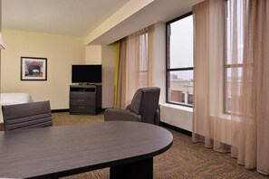 Une chambre d’hôtel équipée d’un lit, d’un bureau, d’une chaise, d’une télévision et d’une fenêtre avec des rideaux.