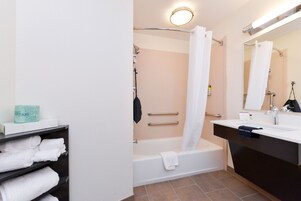 A modern bathroom with a bathtub, a shower curtain, a towel rack, and a sink with a mirror.
