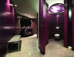 A modern bathroom with a vanity, a toilet, and a bench.