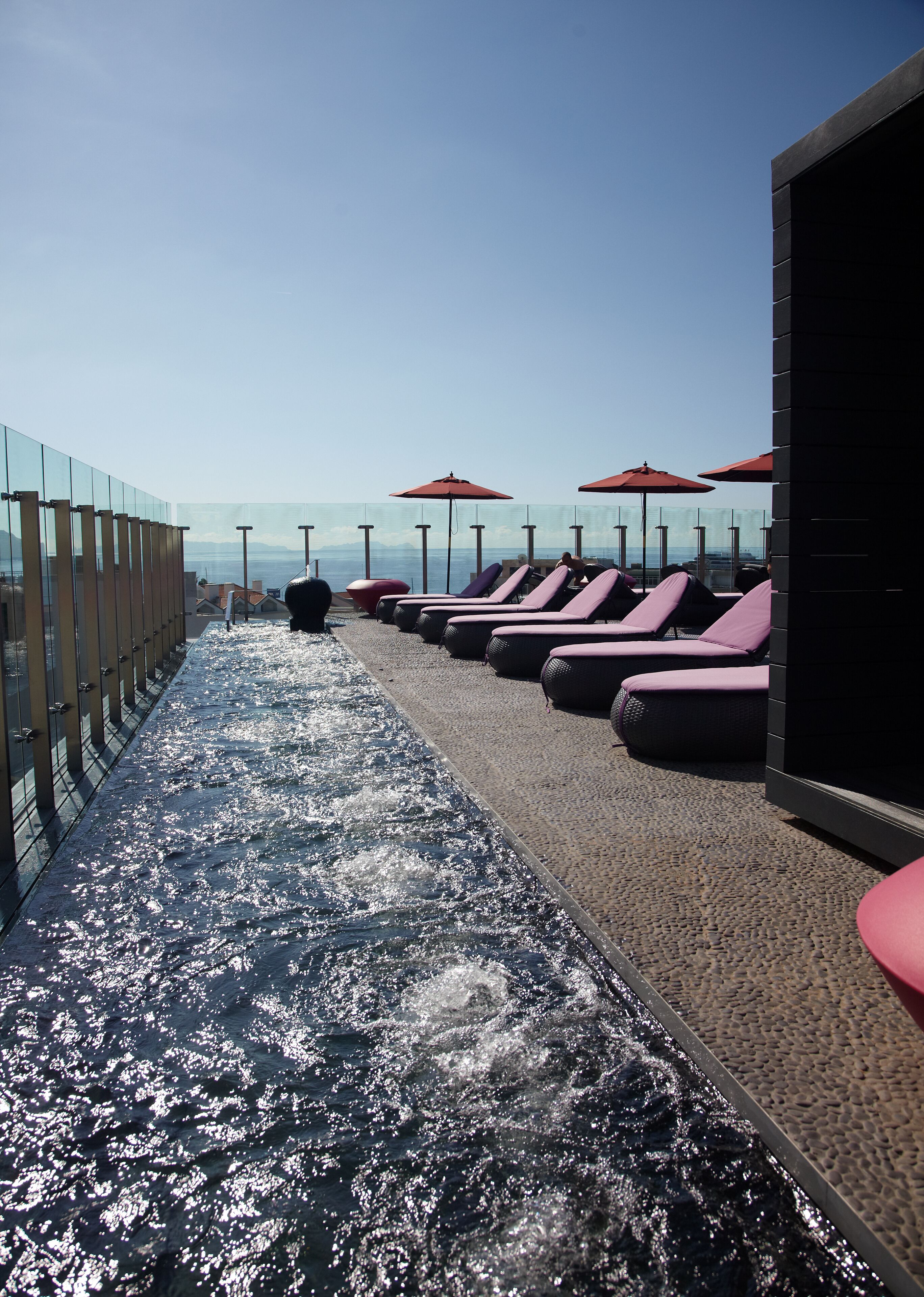 A sun deck with lounge chairs and umbrellas, overlooking a body of water.