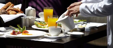 A breakfast table with croissants, a pitcher of orange juice, and a cup of coffee.
