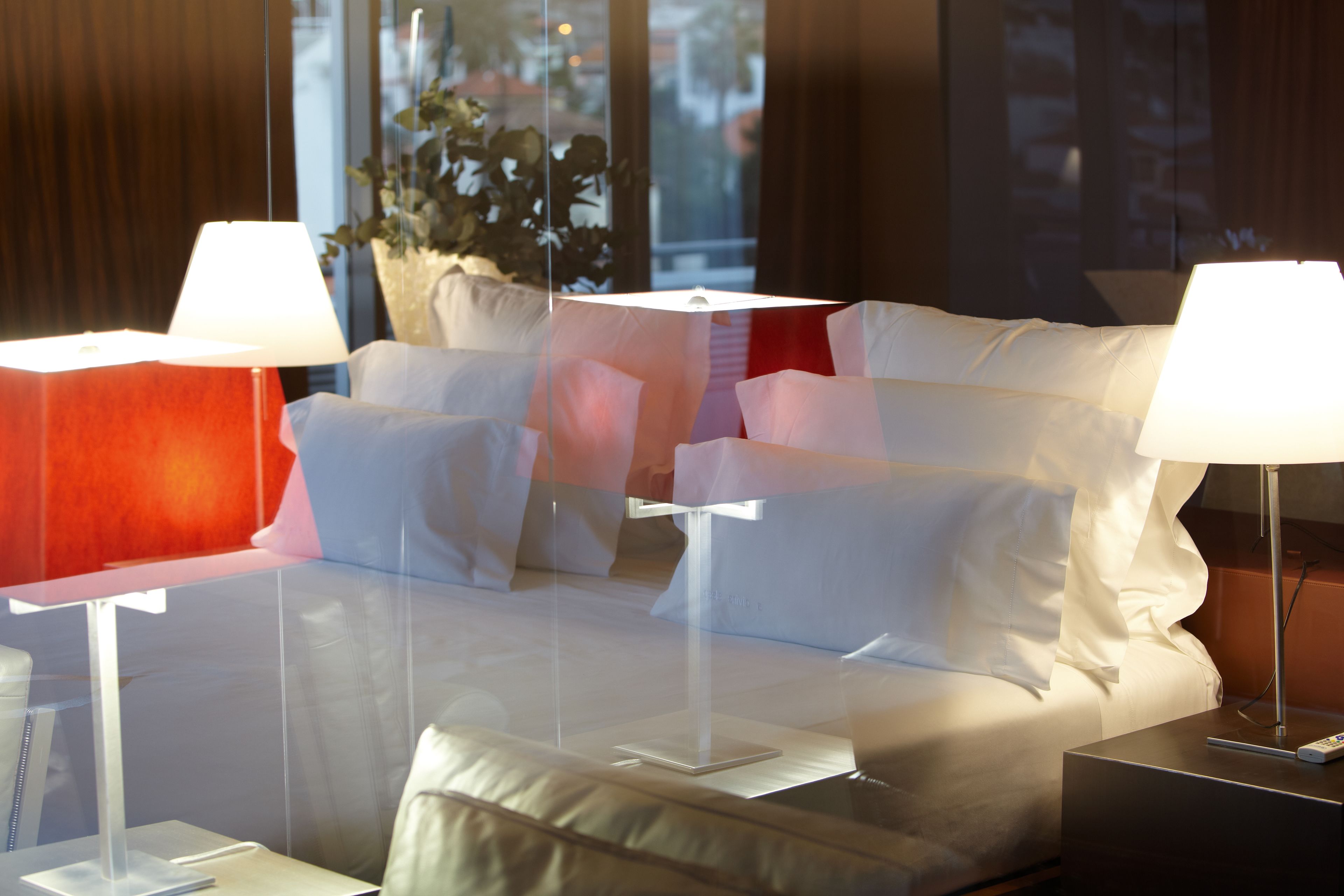A hotel room with a bed, two bedside tables, and a potted plant.
