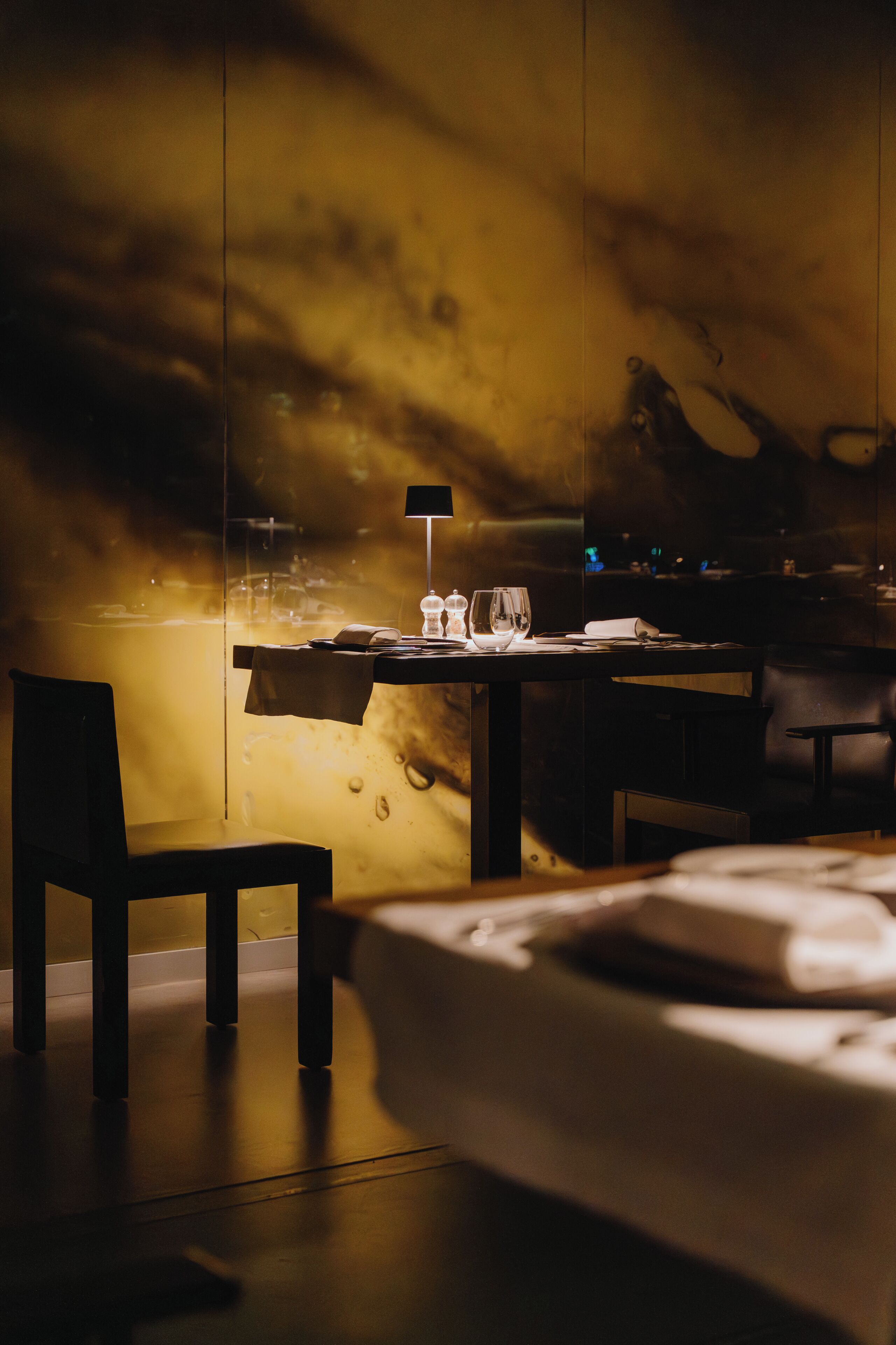 A dimly lit room with a table, chairs, and a bed.