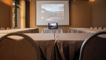 A conference room with a long table, chairs, a laptop on a table, and a projection screen displaying "6 SENSES".