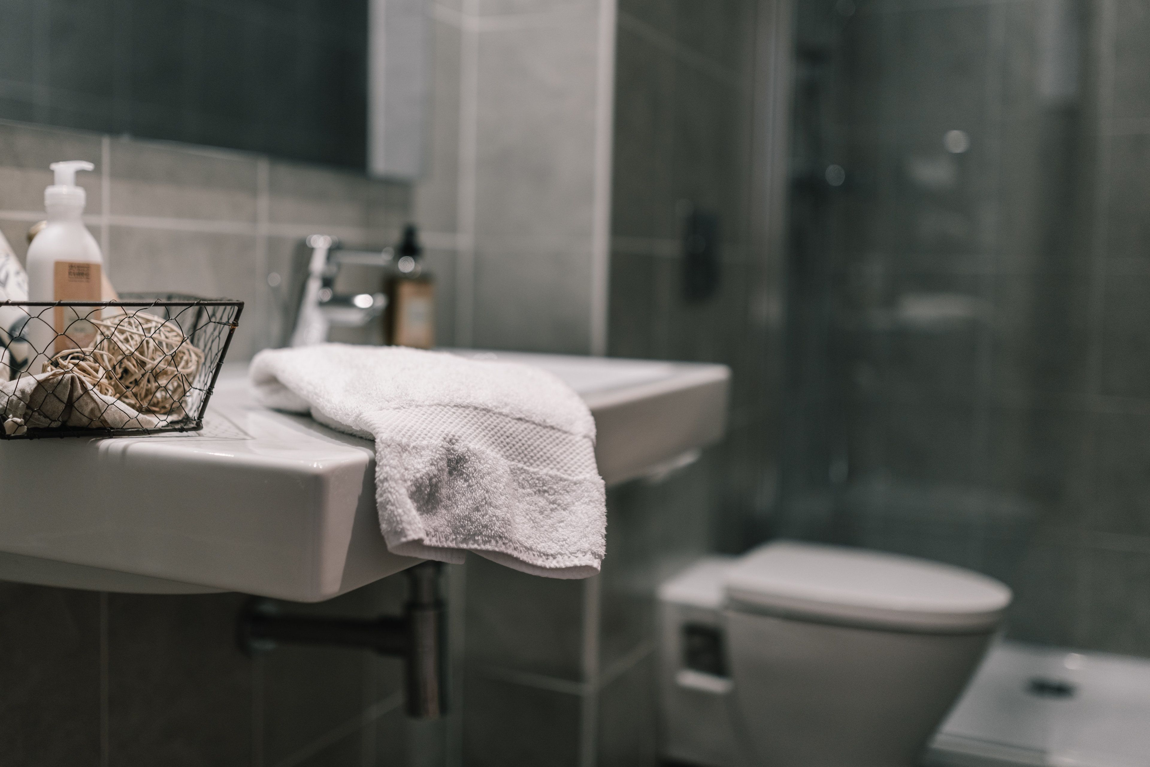 Een badkamer met een witte wastafel, een handdoek en toiletartikelen.