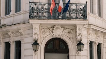 Un edificio histórico con arquitectura ornamentada, un balcón con banderas y un letrero que indica que es un hotel.