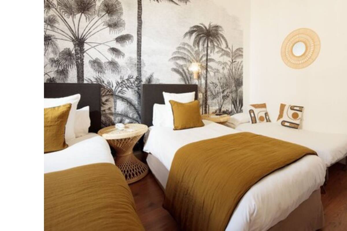 A hotel room with two beds, a round table, and a wall mural.
