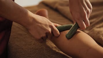 A person receiving a massage with a green tool on their leg.