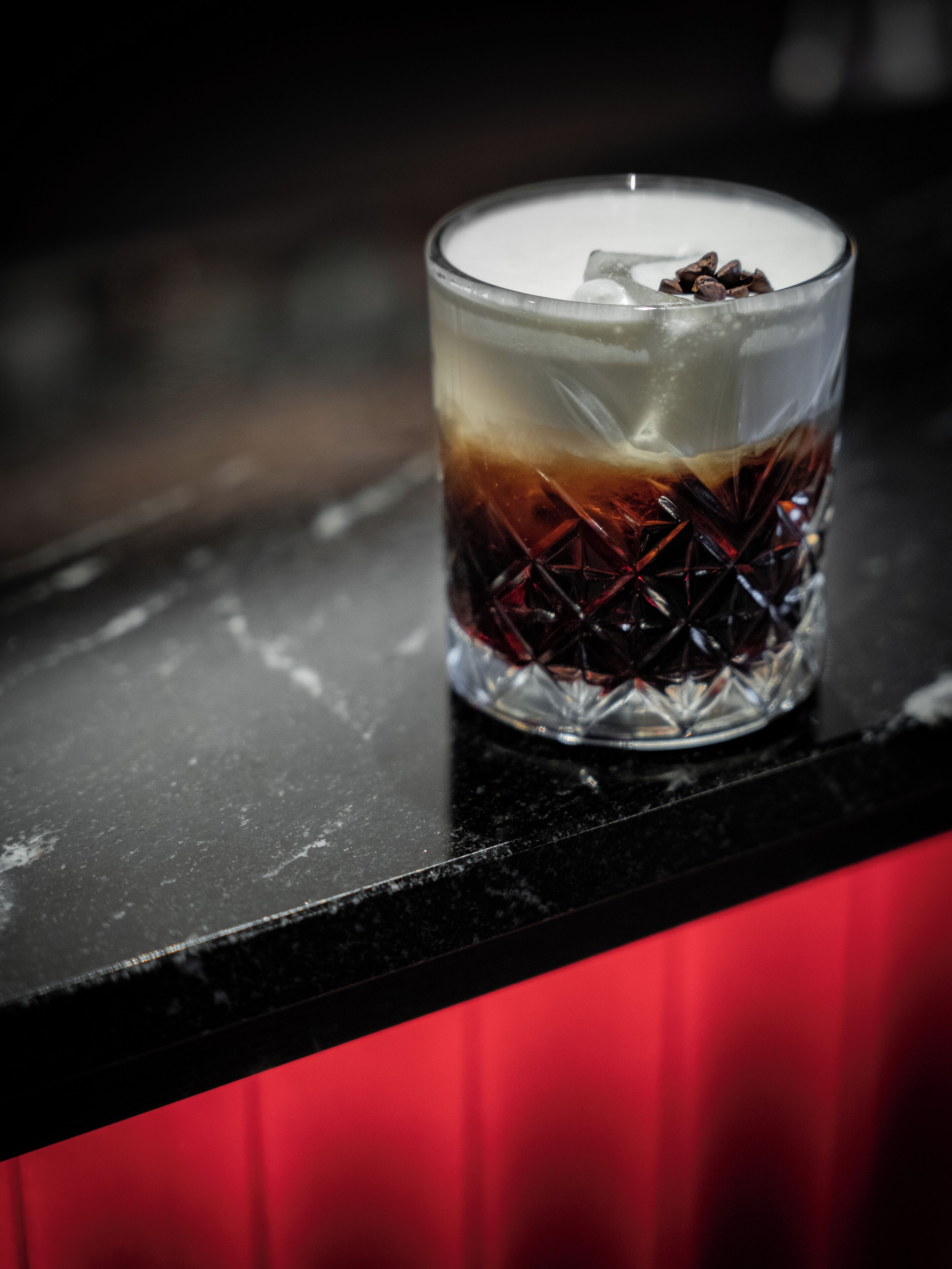 Un vaso con bebidas en capas sobre una encimera negra.