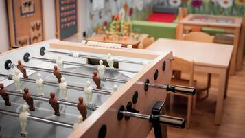 Una mesa de fútbol de mesa en una habitación con muebles de madera y carteles educativos en las paredes.