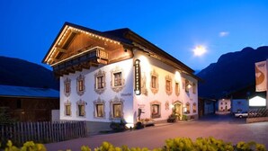 A traditional Alpine-style building with a balcony, a sign indicating it is a restaurant, and a mountain backdrop. - Genuss-Boutique B&B Wienerhof (Trins)