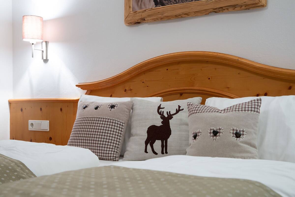 A bed with a wooden headboard, a nightstand with a lamp, and decorative pillows with animal prints.