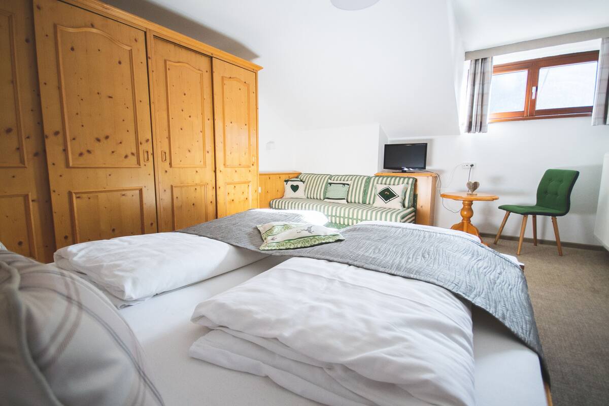 A hotel room with a bed, a TV, a desk, and a chair.