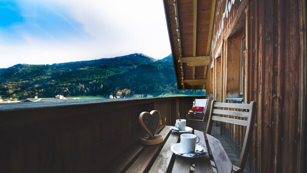 A wooden balcony with a table and chairs, overlooking a mountainous landscape. - Genuss-Boutique B&B Wienerhof (Trins)