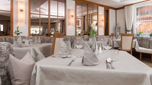 A restaurant with multiple tables set for dining, featuring a modern interior with large windows and decorative lighting. - Genuss-Boutique B&B Wienerhof (Trins)