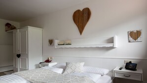 A neatly arranged bedroom with a large bed, a bedside table with a tablet, and a wardrobe. - Genuss-Boutique B&B Wienerhof (Trins)