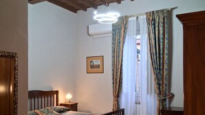 Un dormitorio con una cama de madera, una mesita de noche, una silla y un armario de madera.