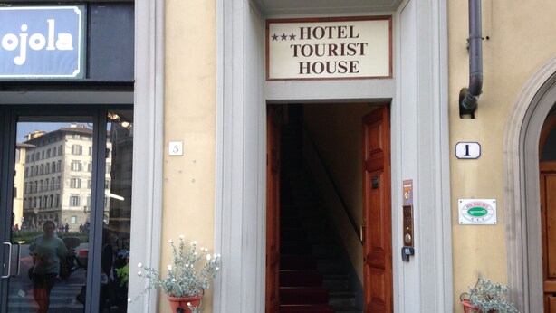Entrada de un hotel con un cartel que dice "HOTEL TOURIST HOUSE".