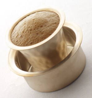 Una taza metálica con una bebida espumosa.