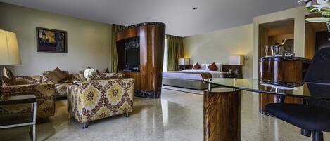 Una habitación de hotel moderna con un conjunto de sofá, una mesa de centro de vidrio, un escritorio con silla y una televisión.