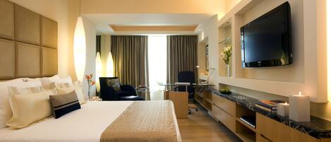 Habitación de hotel moderna con una cama grande, un escritorio, un televisor de pantalla plana y vistas al exterior.