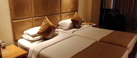 Habitación de hotel con una cama grande, una mesita de noche de madera y un cabecero con diseño acolchado.