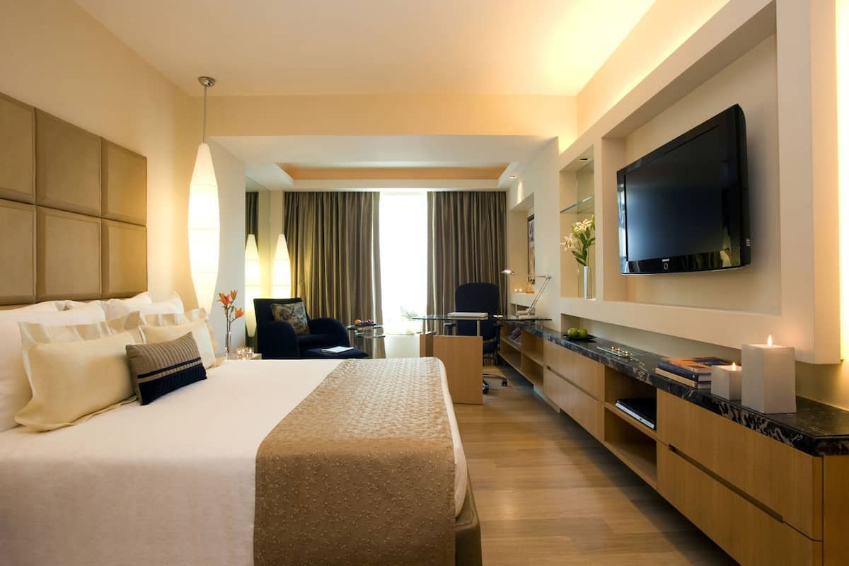 Ein Hotelzimmer mit Bett, Schreibtisch, Stuhl, Fernseher und Blick ins Freie.