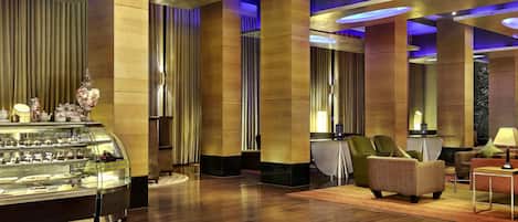 A modern lobby with a glass display case, plush seating, and a chandelier.