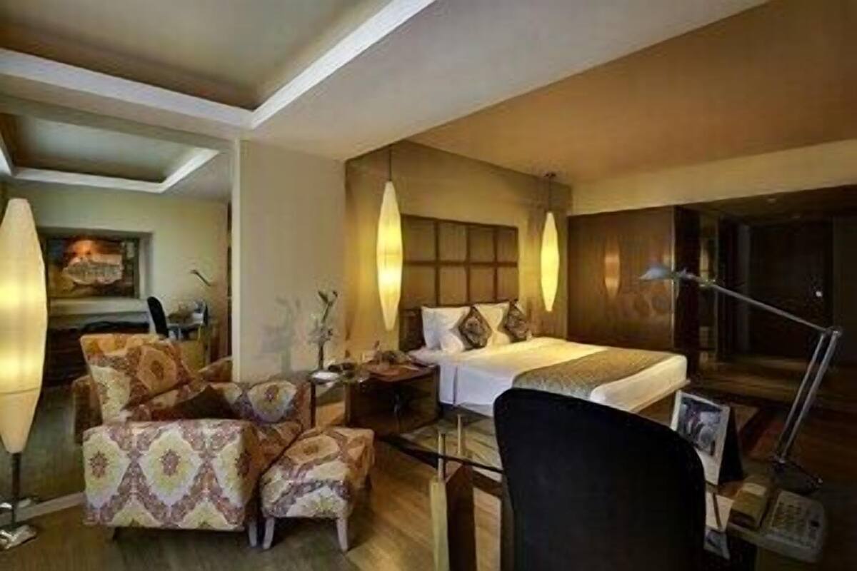 Ein Hotelzimmer mit einem Bett, zwei Sesseln, einem Schreibtisch und einer Lampe.
