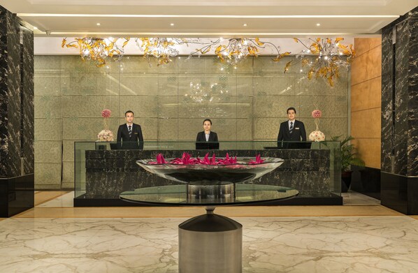 A reception area with a marble floor, a glass reception desk, and a decorative fountain.