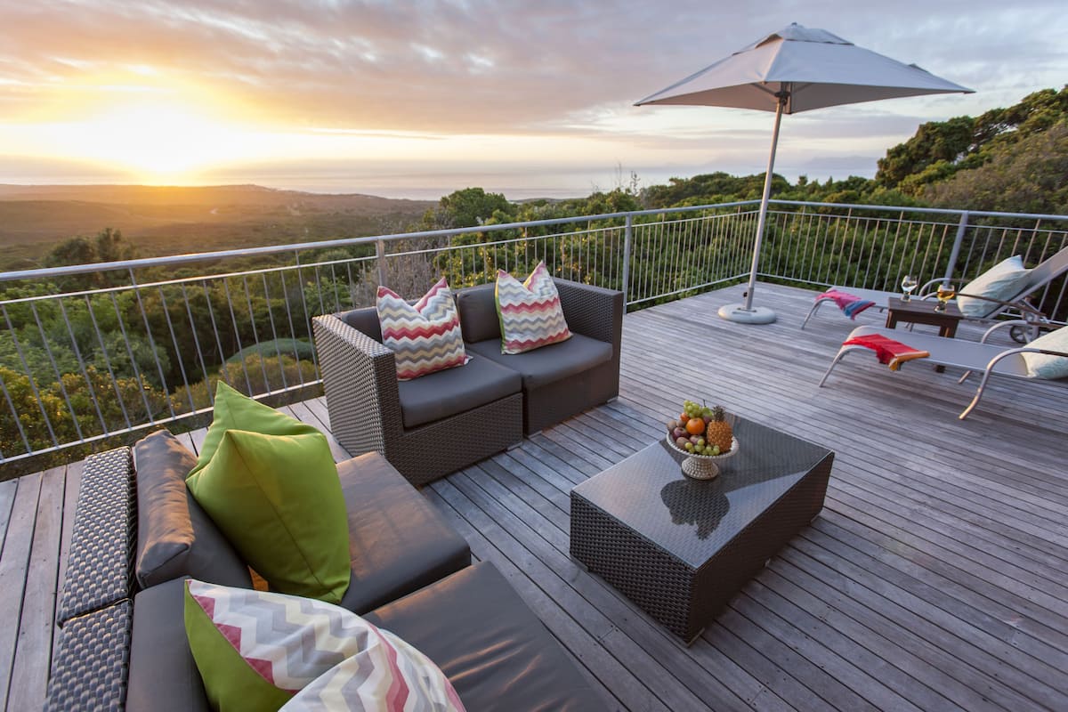 A deck with outdoor furniture, including sofas and chairs, and a table with fruit.