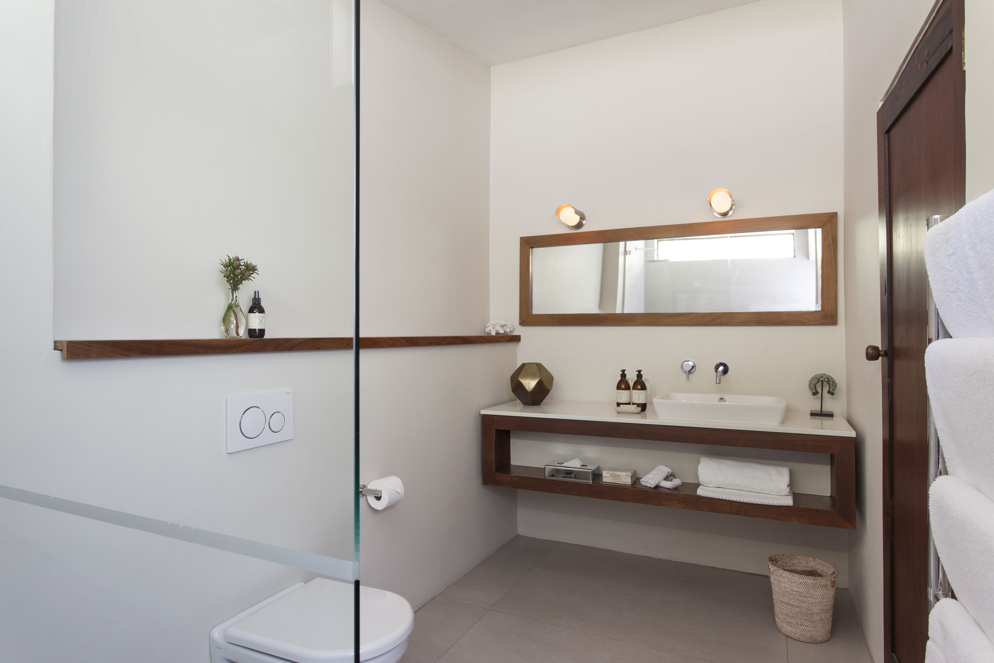 A bathroom with a toilet, sink, mirror, and towel rack.