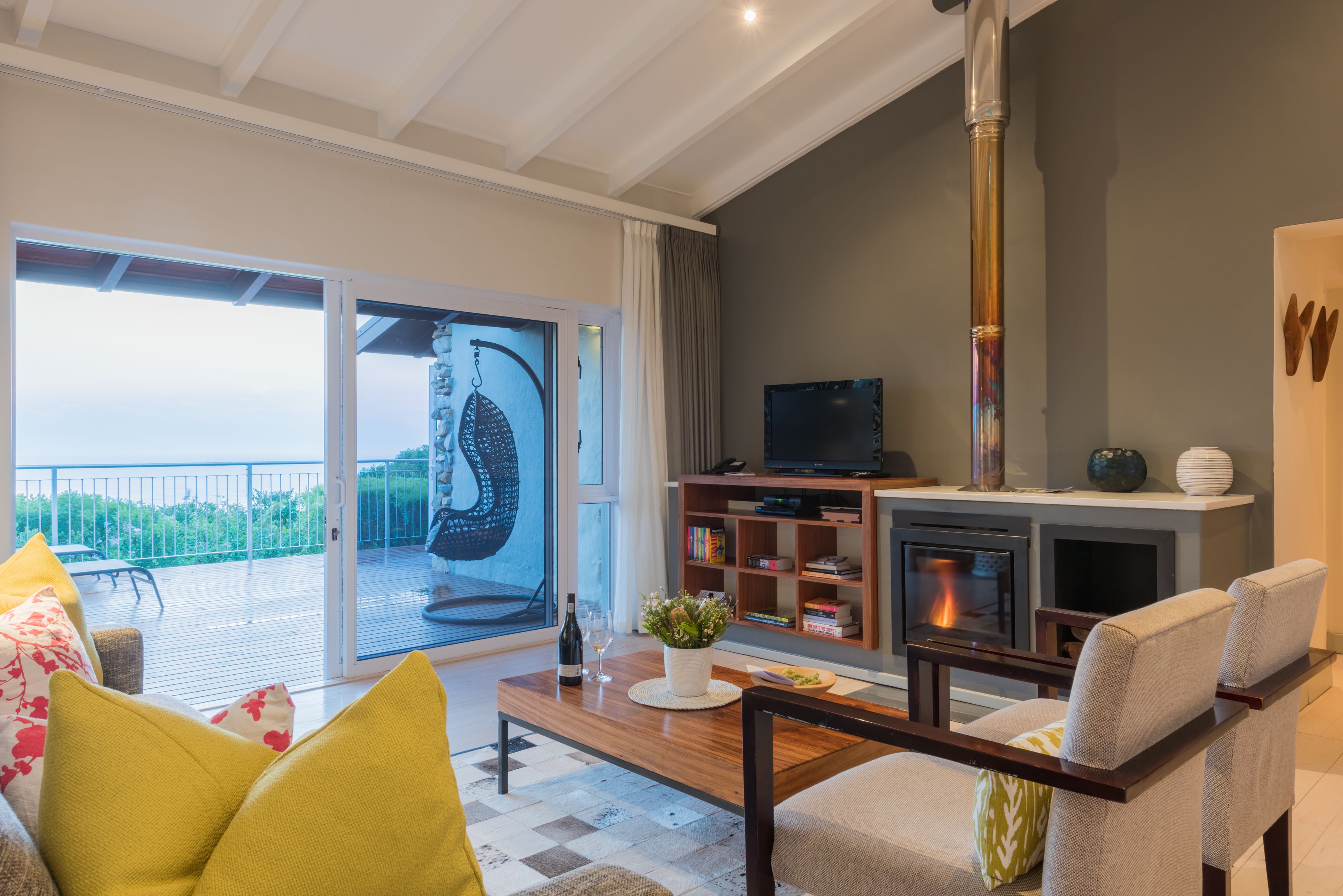 A modern living room with a fireplace, a television, and a balcony with a view.
