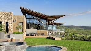 Una casa moderna con piscina, fachada de piedra y amplios ventanales.