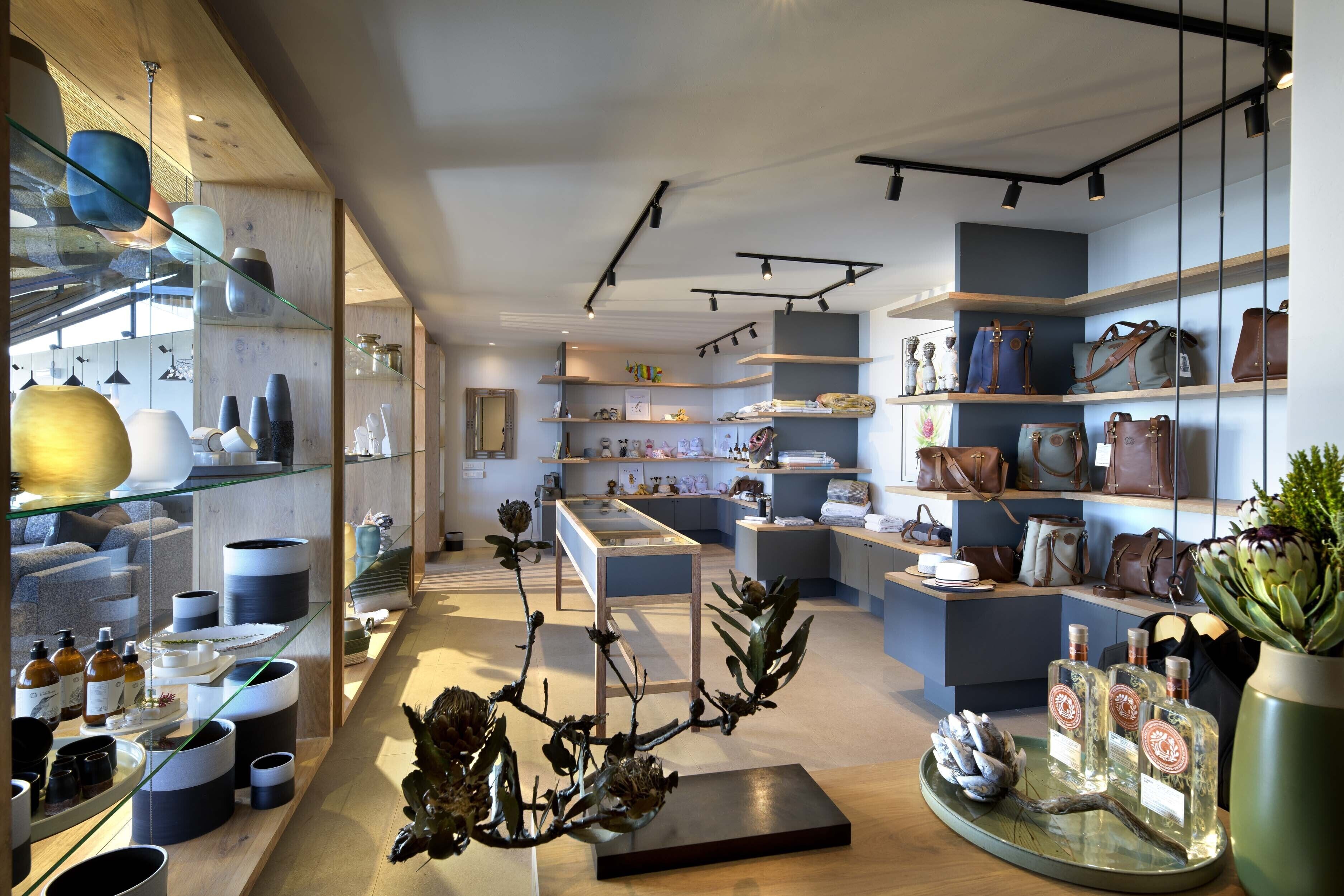 L’intérieur d’un hôtel-boutique moderne, avec des vitrines, des étagères où sont exposés des sacs à main et des objets décoratifs.