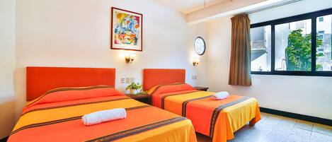 A hotel room with two beds, a ceiling fan, a window with a view, and a clock on the wall.