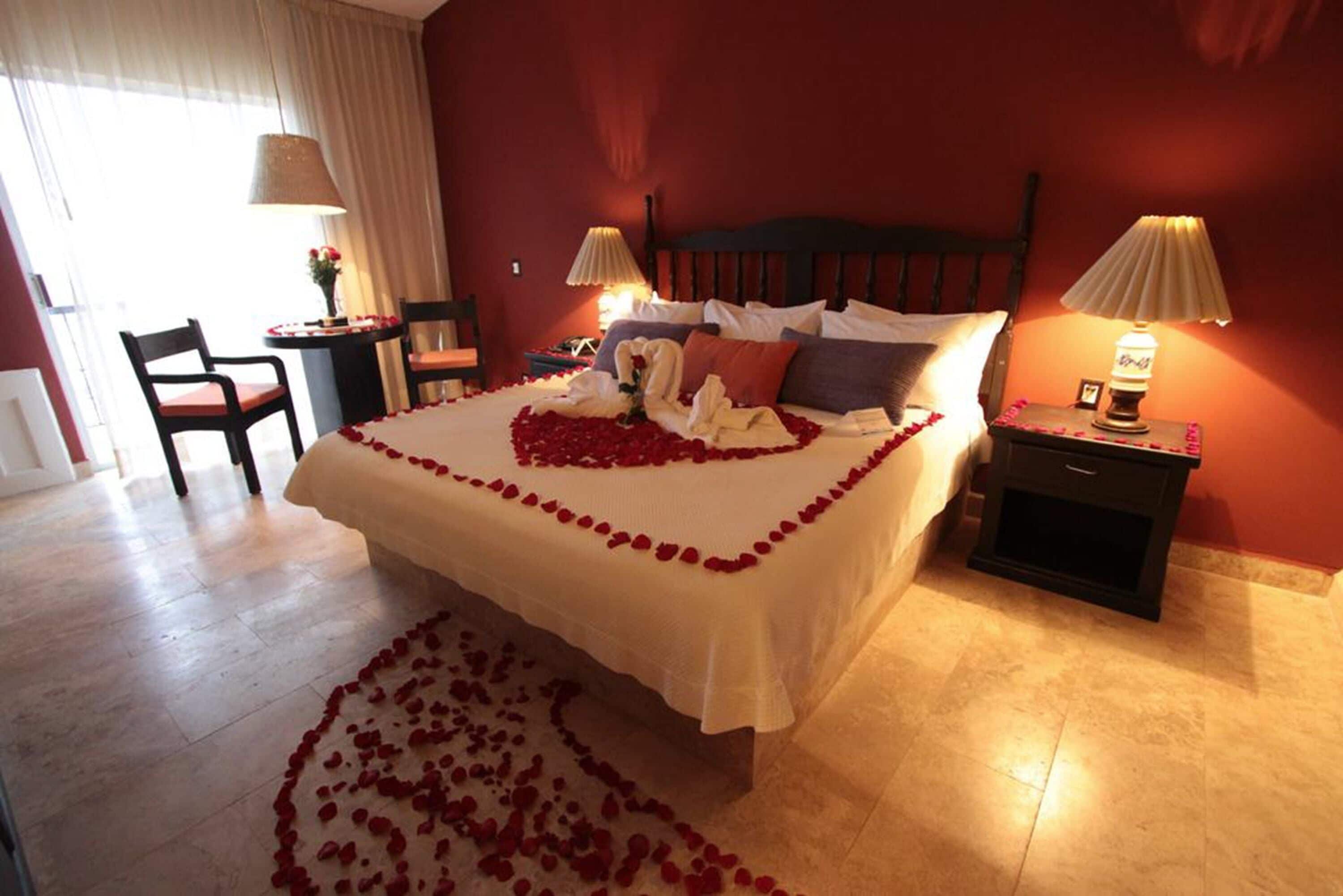 A hotel room with a large bed, two bedside tables, a chair, and a lamp.