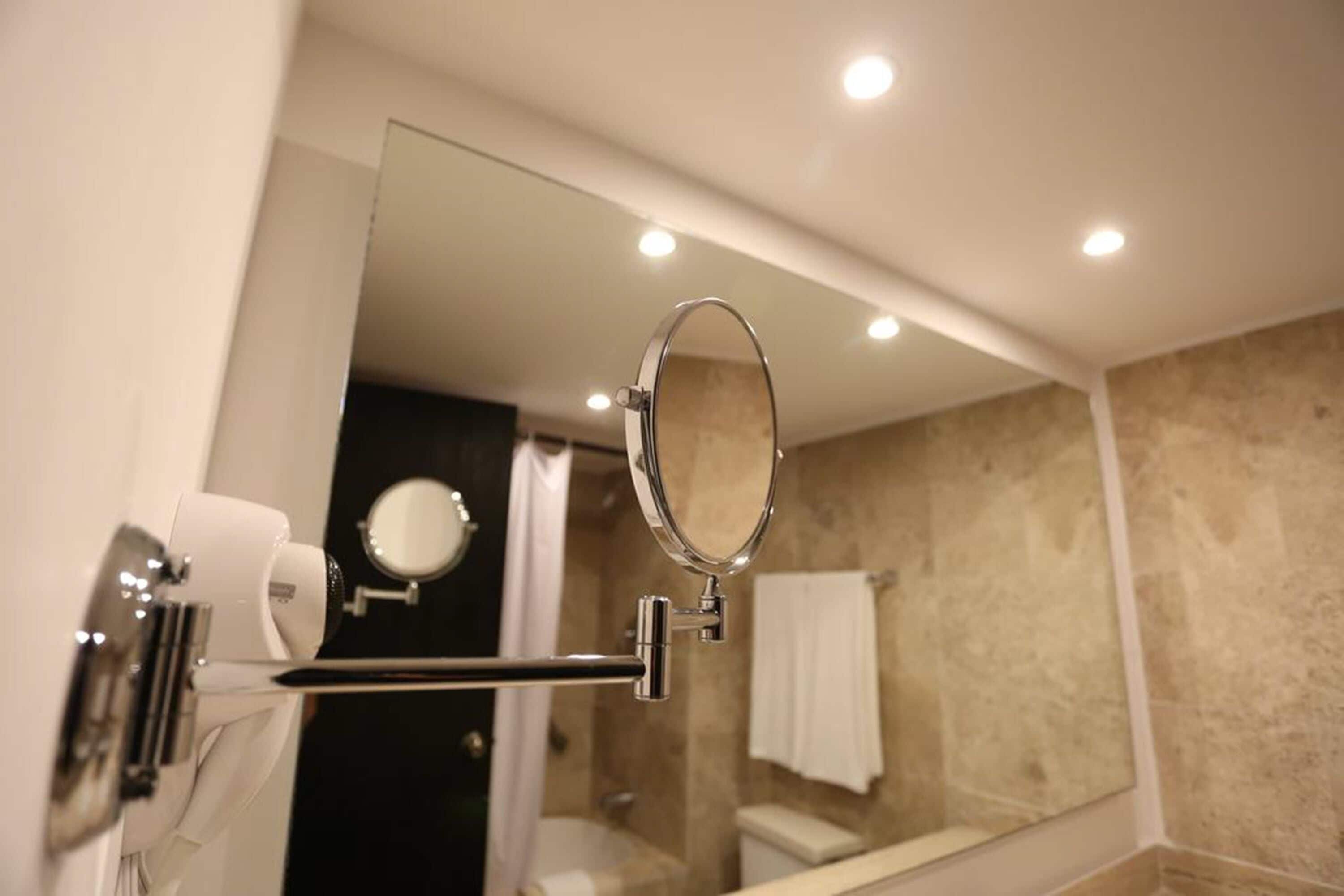 Ein Badezimmer mit einem großen Spiegel, einem Handtuchhalter und einer im Spiegel sichtbaren Toilette.