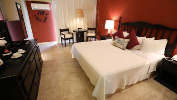 Habitación de hotel con una cama grande, un escritorio con lámpara, una silla y una mesita.