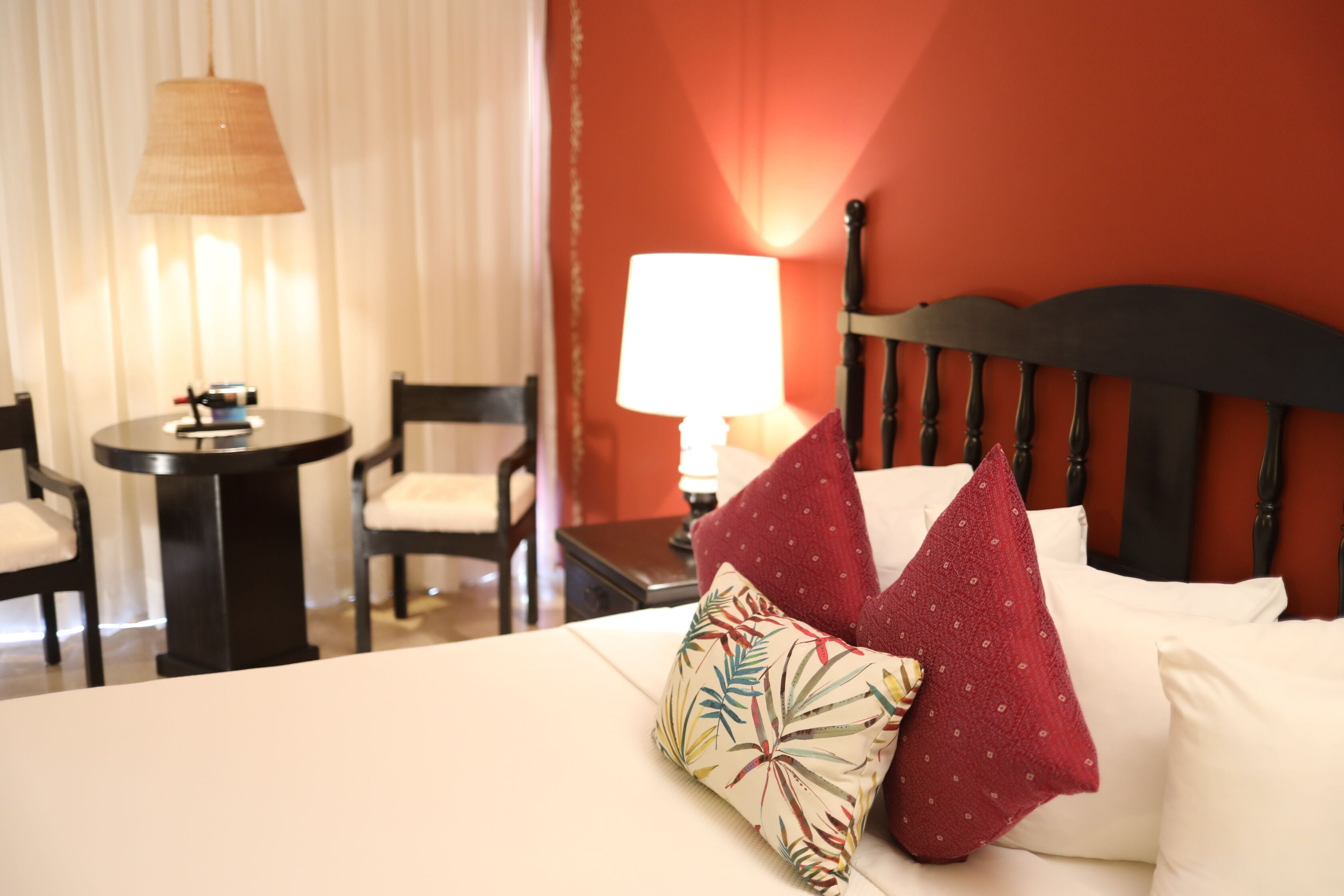 Una habitación de hotel con cama, mesita de noche con lámpara, una silla y una mesa.