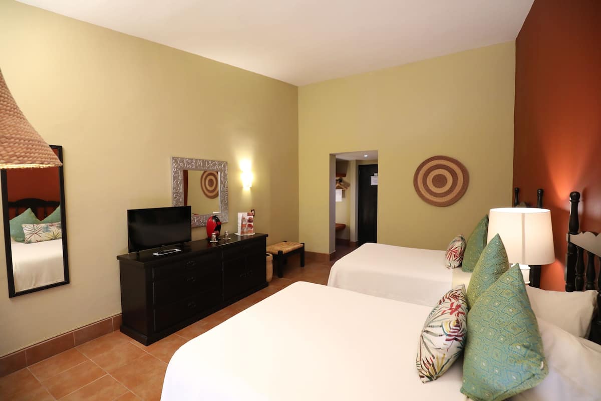 A hotel room with two beds, a TV on a dresser, and a mirror on the wall.