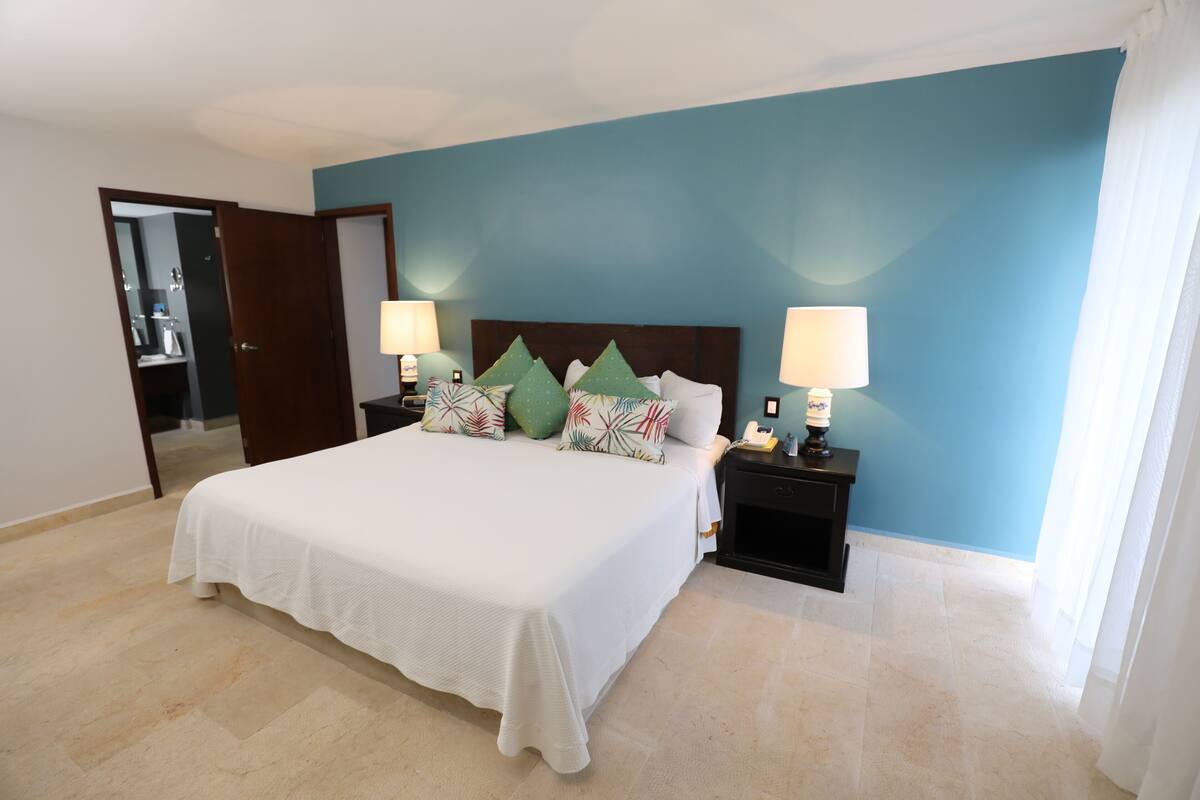 A bedroom with a large bed, two bedside tables with lamps, and a mirror on the wall.