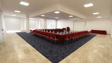 Una sala de conferencias con una larga mesa, sillas rojas y una alfombra oscura.