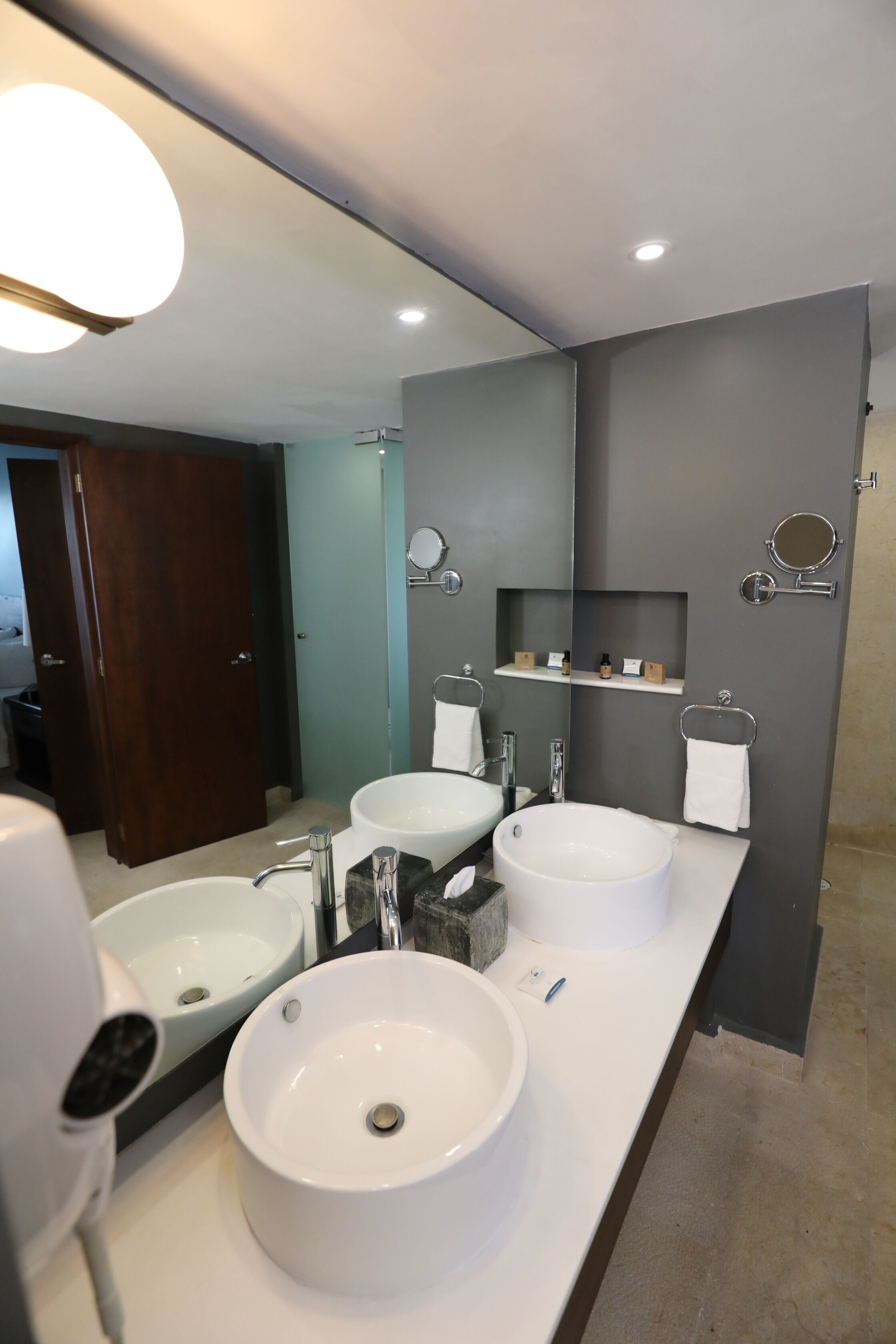 A modern bathroom with two sinks, a large mirror, and a towel rack.