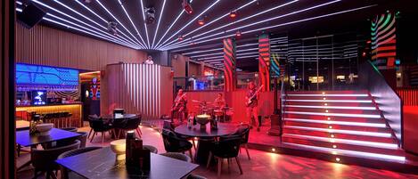 Un espace bar moderne doté d’une cabine de DJ, de sièges et d’un escalier dont les marches sont illuminées.