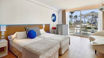 A modern hotel room with a large bed, a desk, and a view of the pool area.