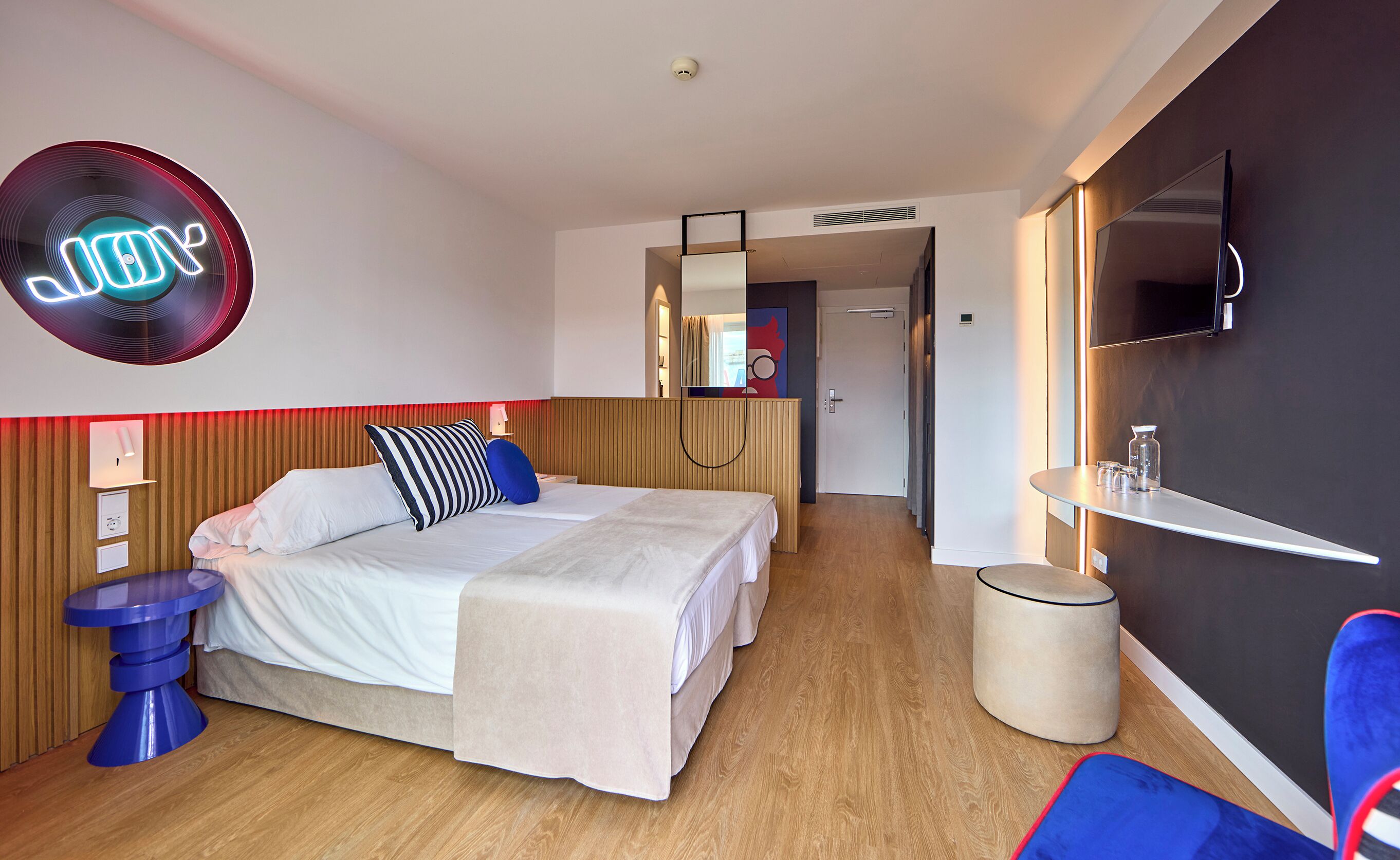 Et moderne hotelværelse med seng, natbord og fjernsyn.