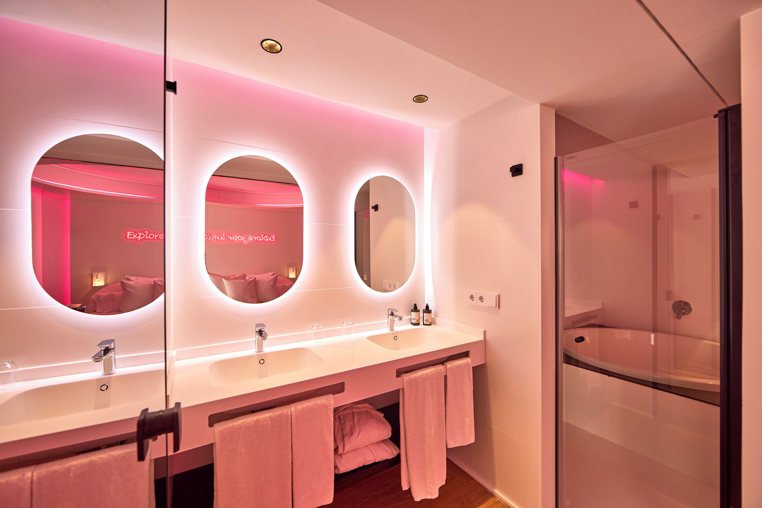 Une salle de bain moderne avec un meuble-lavabo, des miroirs et une cabine de douche en verre.