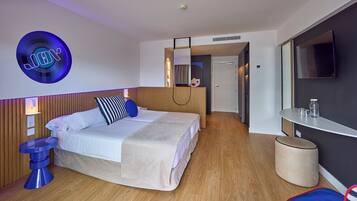 A modern hotel room with a bed, bedside table, and a round mirror.