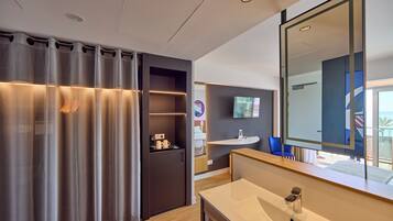 A modern bathroom with a large mirror, a sink, and a shower area.